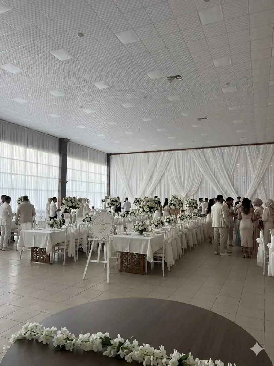 Kapalı salonda beyaz örtülü uzun masa düzeni